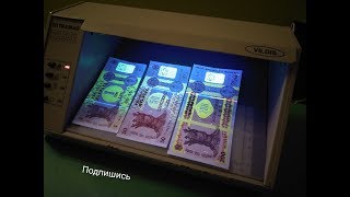 Купюры под ультрафиолетом. Прибор из банка показывает скрытые знаки денег разных стран
