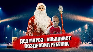 Дед Мороз поздравляет ребенка  спустившись с крыши. Santa Claus climber congratulates a child.