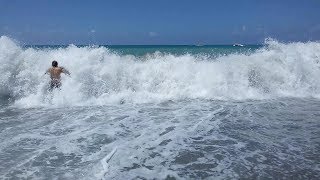 Огромные волны уносят людей с пляжа в море.
