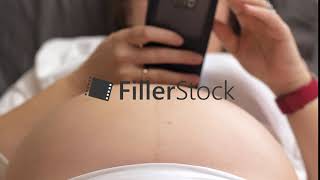 Pregnant woman with cell, baby kicking the belly